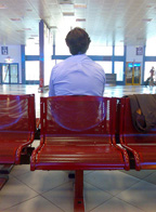 Fotografía de un hombre sentado solo de espaldas.