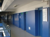 En la foto se aprecia un pasillo de la empresa donde están las puertas de los distintos departamentos.  Pasillo y puertas están pintados de color azul.