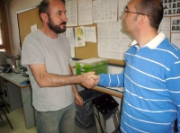 En la foto se ve a dos trabajadores de pié en una oficina charlando y dándose la mano.