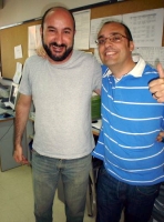 Dos jóvenes compañeros de trabajo miran sonrientes y abrazados a la cámara.