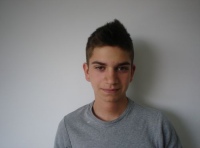 En la foto se ve el busto de un joven con camiseta gris mirando de frente a la cámara.