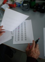 Un administrativo repasa un listado.  Se pueden observar los folios y la mano del administrativo sujetando un rotulador fluorescente.