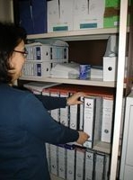 Una administrativo busca una carpeta dentro de un armario.  Foto realizada desde la parte posterior.