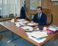 Decisiones. Se observa a un directivo con traje de color oscuro en su mesa de despacho con gran cantidad de documentación sobre ella.