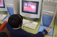  Imagen de  una persona sentada ante el ordenador usando auriculares y micrófono.