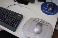 Imagen, de un puesto de trabajo donde se destaca le ratón sobre una alfombrilla  ergonómica.